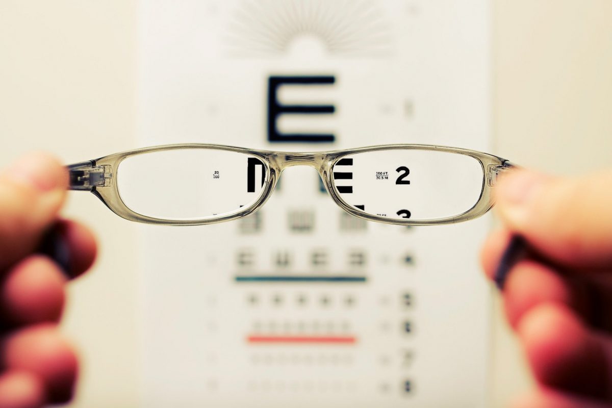glasses held in front of eye exam chart