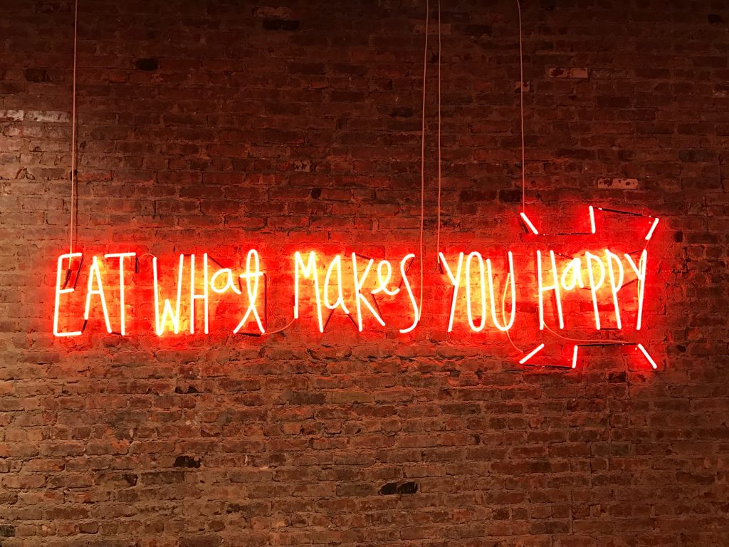 a neon sign that says ‘Eat What Makes You Happy