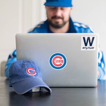 Designer sitting in front of a laptop with a Chicago logo and Chicago Cubs hat