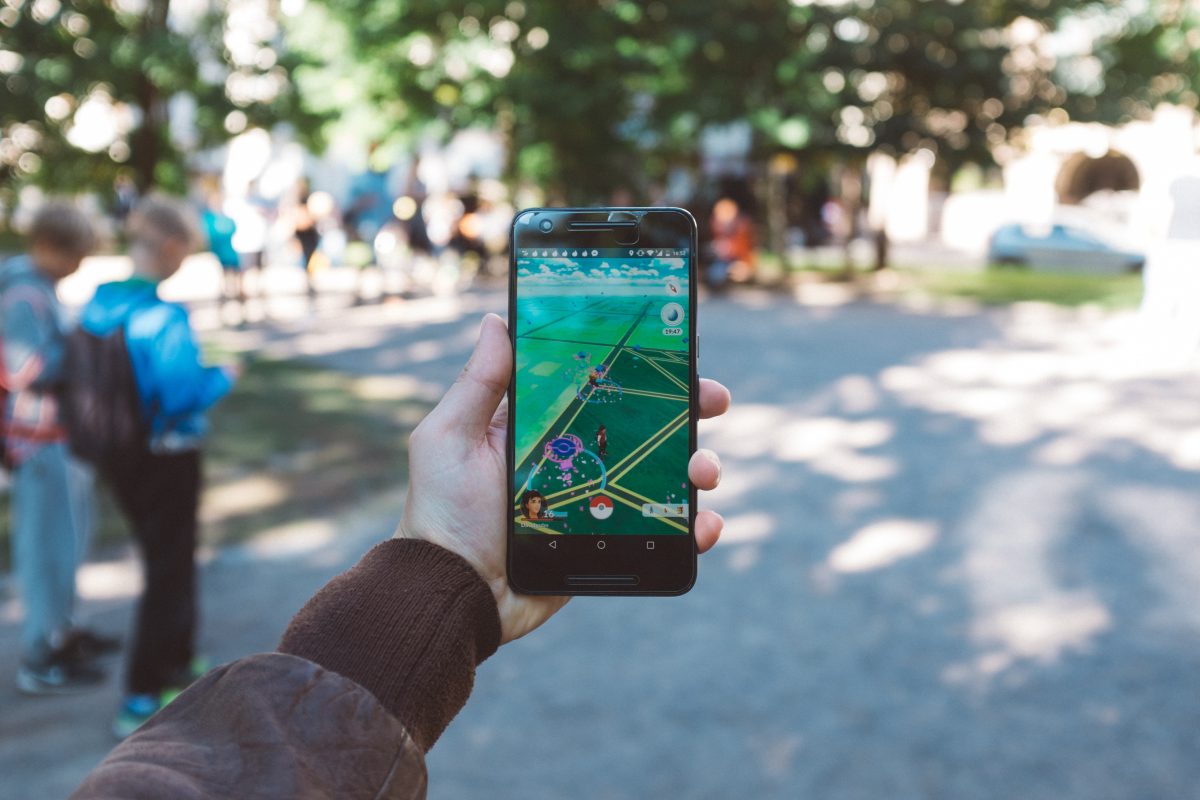 Phone held in outstretched hand, screen shows that user is playing Pokémon Go