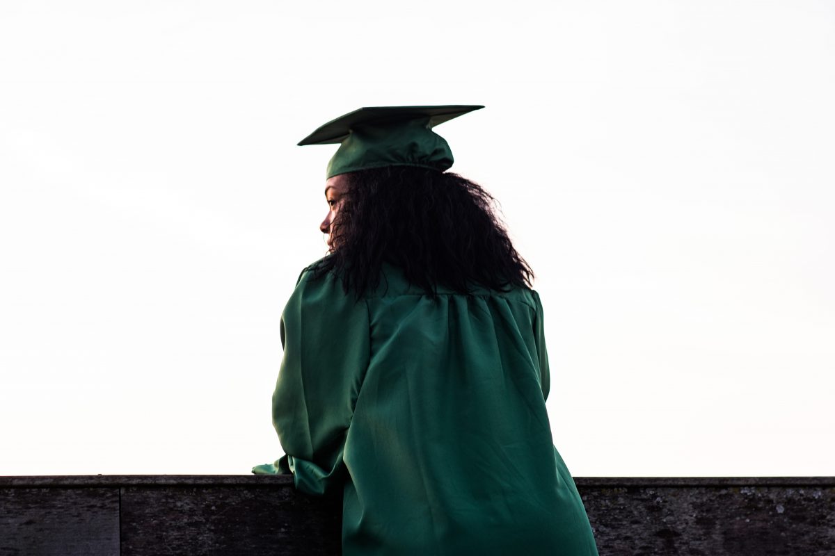 Student in cap and gown looking beyond view