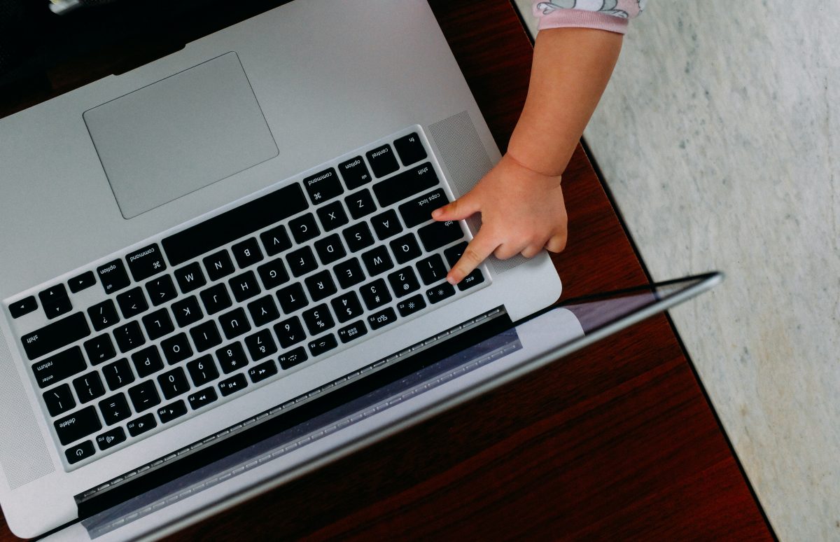 baby hand reaching to type on a computer's keyboard