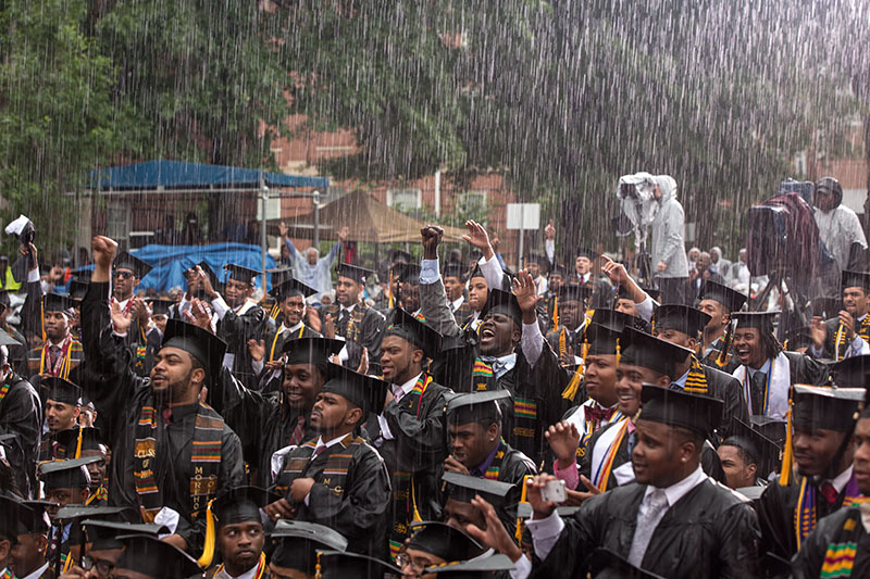 Students in caps and gowns celebrating in the rain