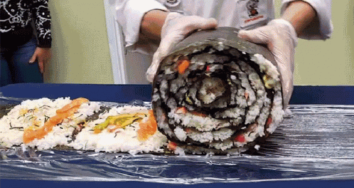A gif of a giant roll of sushi being formed