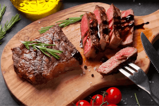 Sliced steak fillet on cutting board with rosemary