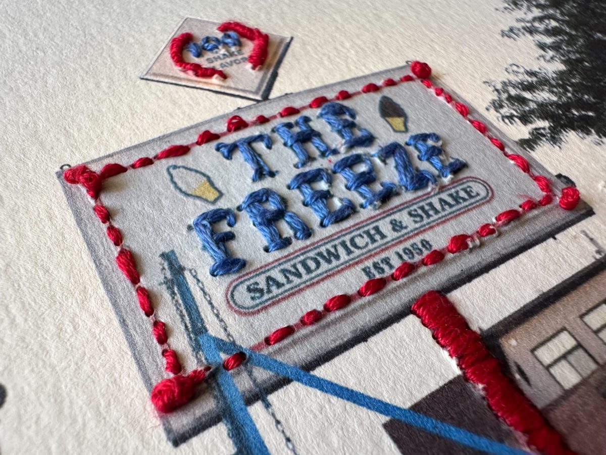 a printed photo of the sign of an ice cream show "The Freeze." The photo has been decoratively embroidered. 