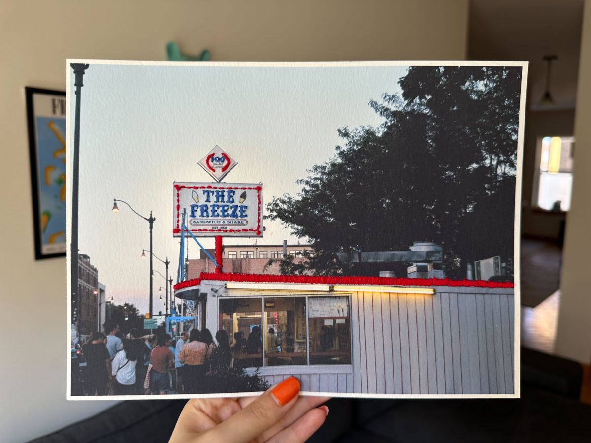 a printed photo of the sign of an ice cream show "The Freeze." The photo has been decoratively embroidered. 